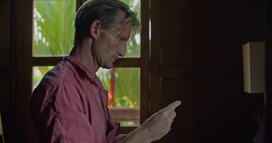 Man turns around a credit card to read the numbers on the back to make an online purchase from the hotel room