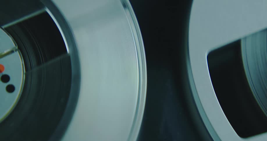 The reels on a reel to reel tape player turn as the tape plays