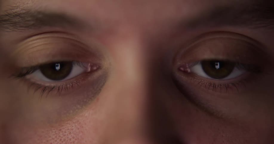 A computer monitor and screen are reflected in the eyes of a person