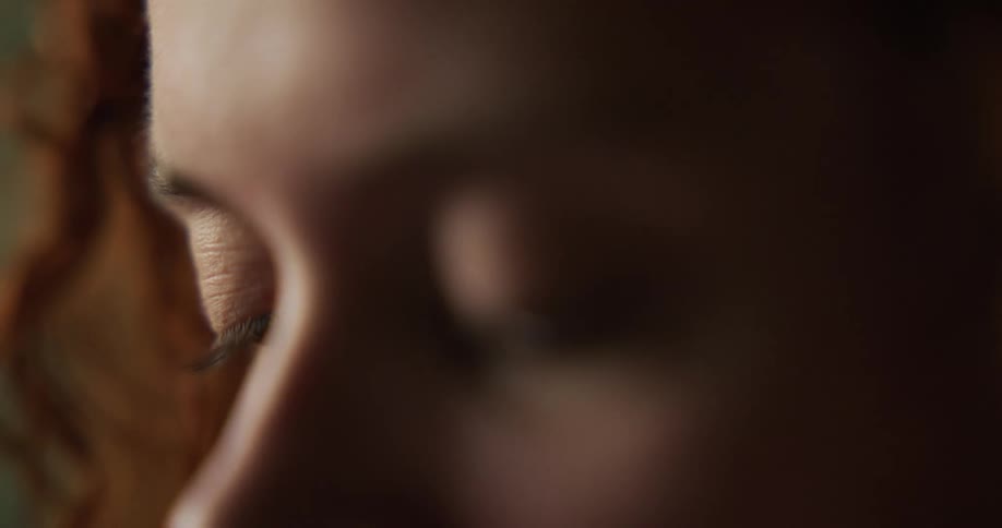 Closeup of woman face with brown wavy hair looking down at smartphone screen