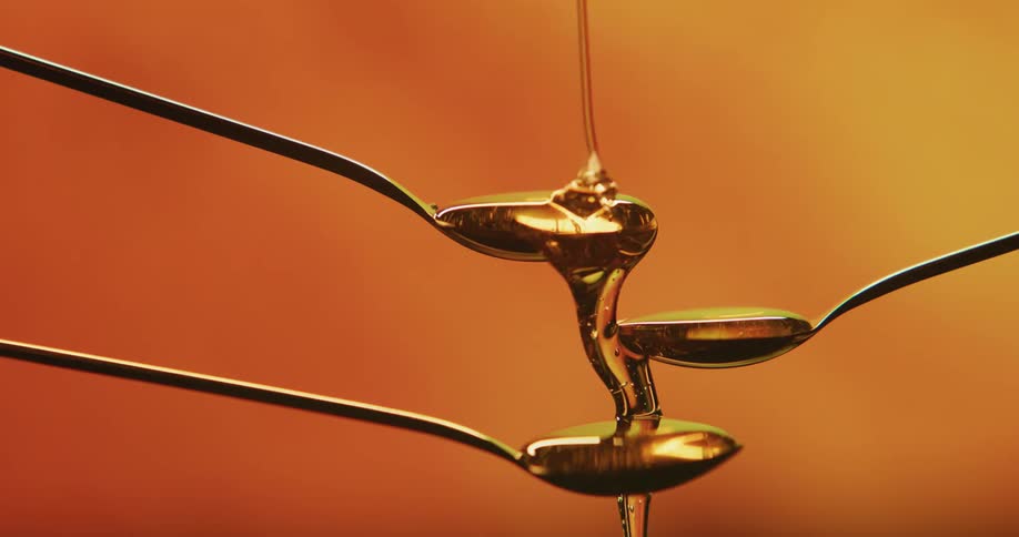 Honey drips down three staggered spoons