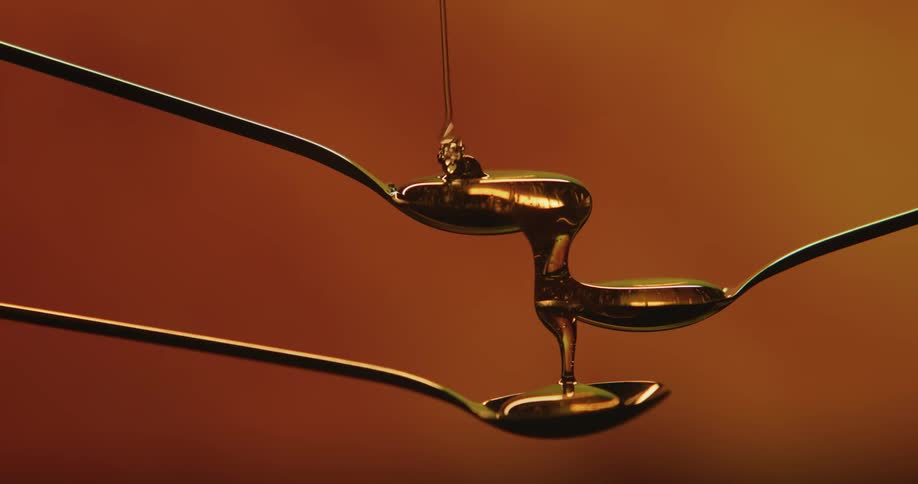 A studio shot of 3 spoons with honey being drizzle on them