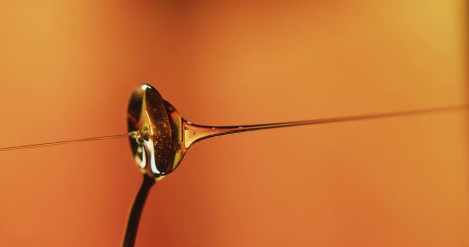 Honey pours down on a spoon and spills over