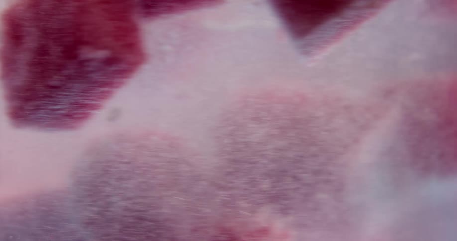Red cubes of various size swirl in fizzy mixture