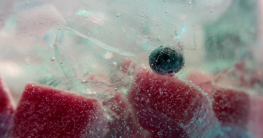 Bubbles flow upward in fizzy container of fruit and ice