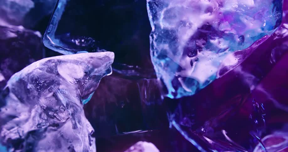 Close up of ice shards floating on a liquid under blue neon lights
