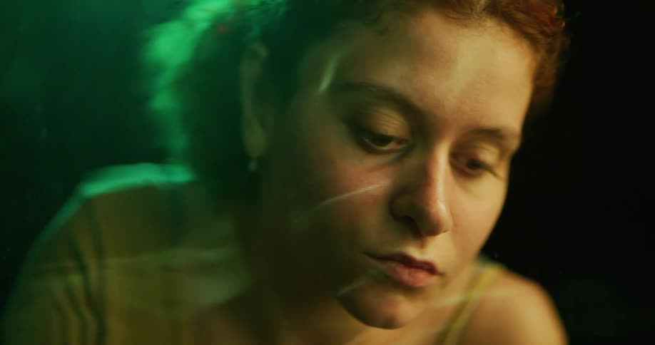 A womans face as she looks down in to water