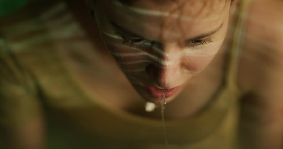 Woman raise head from water and continues leaning over as water drips and reflected light plays across her features