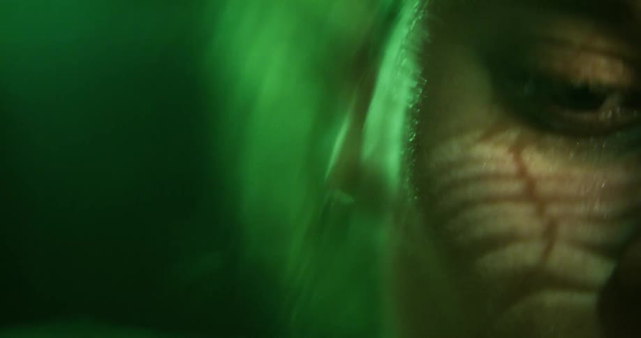 Close up of the face of a woman submerged in water reflecting bright green light