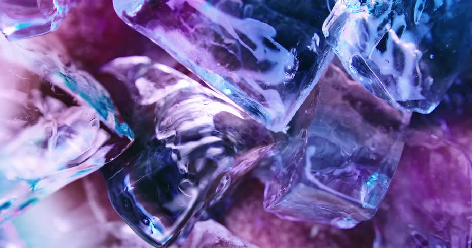 Close up of ice cubes floating on water under colorful neon blue lights