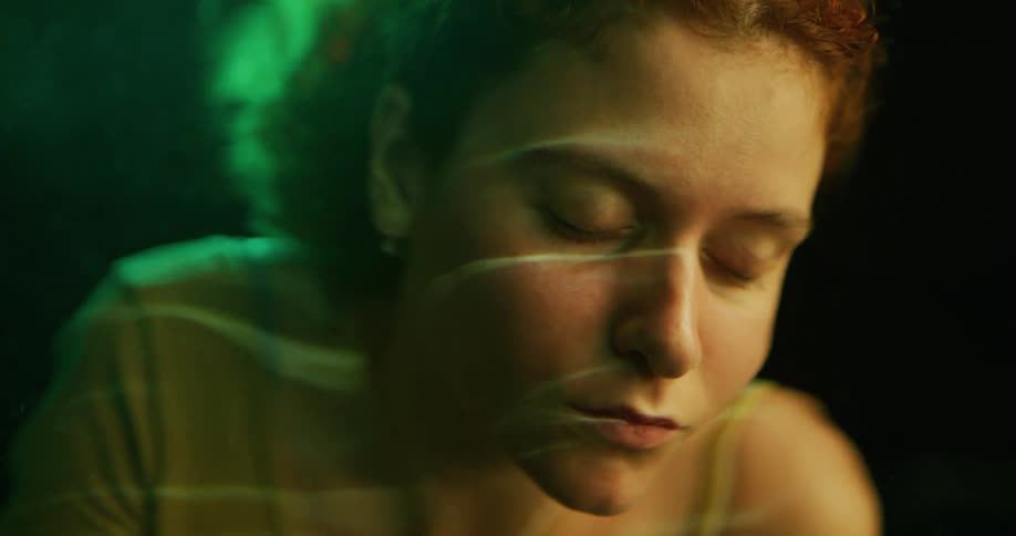 A woman with her eyes closed and face reflected on the surface of clear water