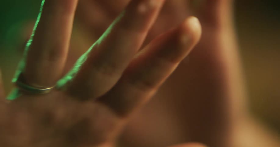 A persons hands are moving and a green light is shining around their fingers