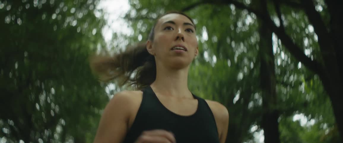 Woman with ponytail and sports bra jogs in public park