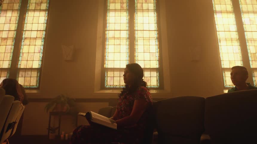 Woman sitting on a chair in a church with an open book over her legs