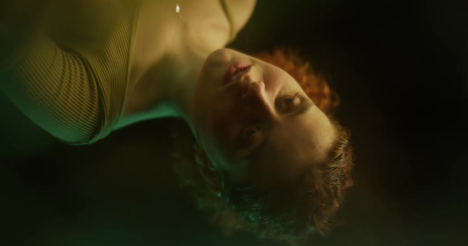 The reflection of a woman on the surface of the water as she looks down into a pool