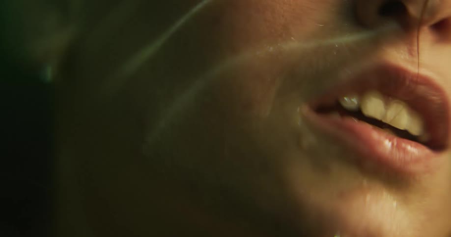 Close up of the mouth of a wet woman dripping water over the surface