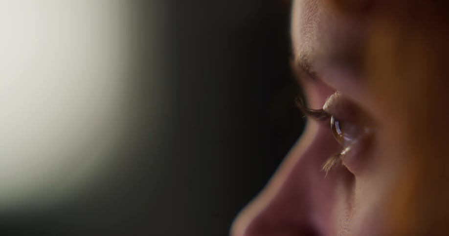 Light reflects on the eyeball of a woman in profile