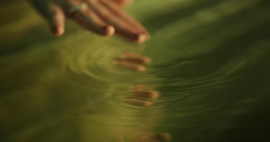 Person moves hands through water showing mirror imagesof reflection of hands