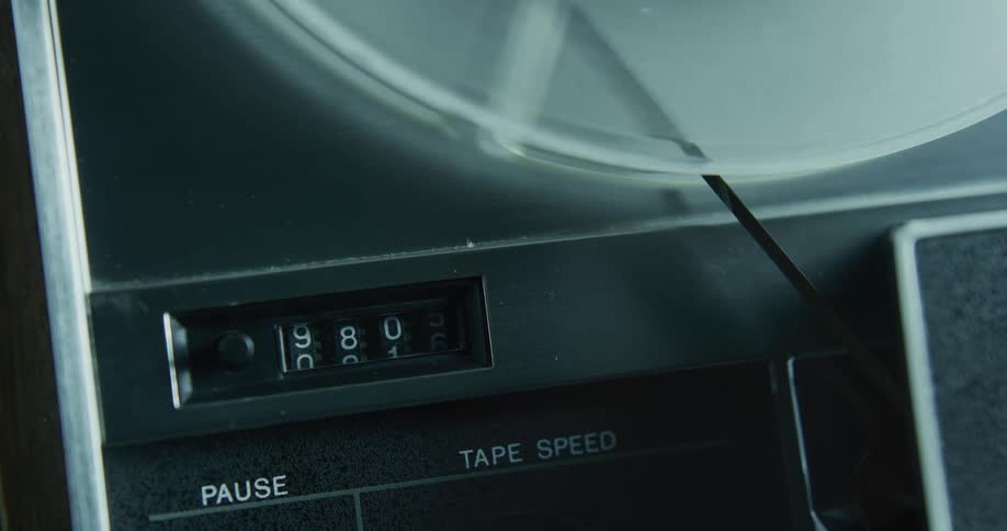 The reel on a reel to reel tape player turns as the tape runs through the machine