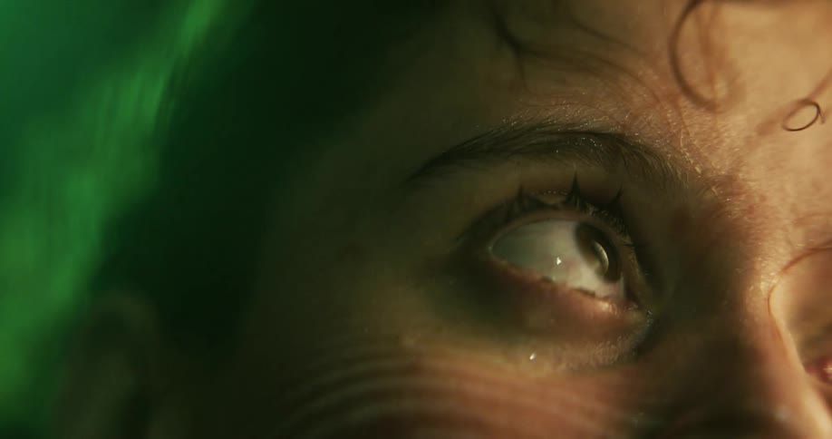 Water ripples near a womans eye as she blinks underwater