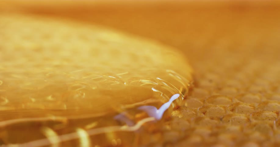 Golden honey poured and flowing onto honeycomb