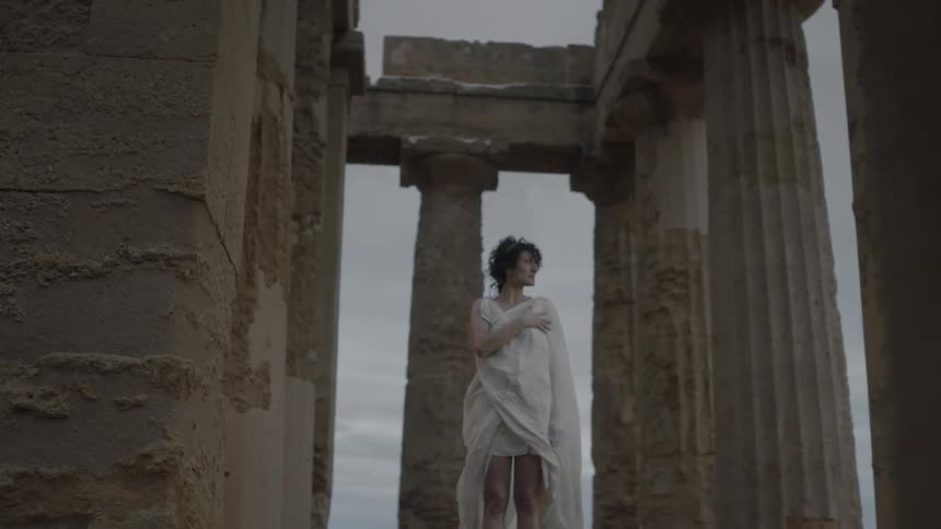 Woman holds her robes outside on a windy day