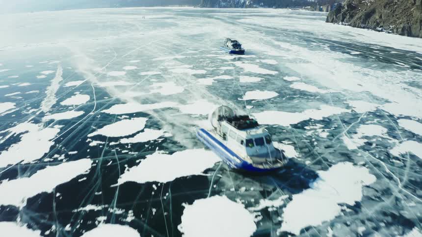 Large machines driving across a frozen lake