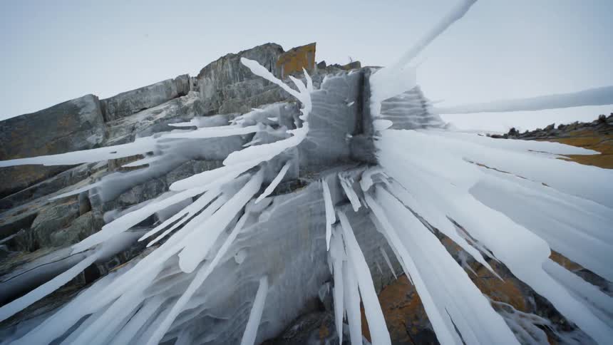 Long icicles hang from a rock formation during the day