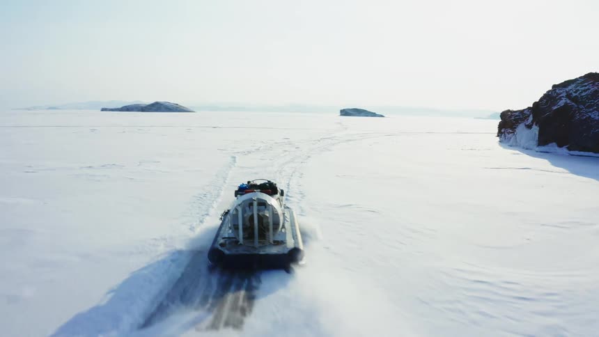 An aerial view of a boat traveling over icy water in the arctic