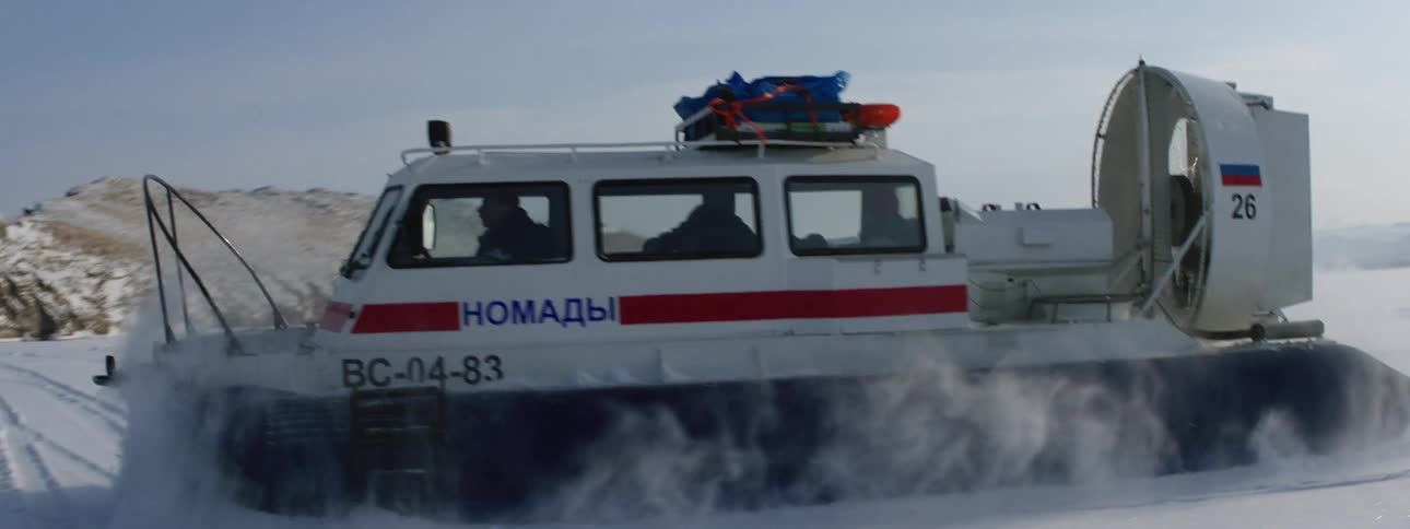 A hovercraft travels through thick snow on icy lake