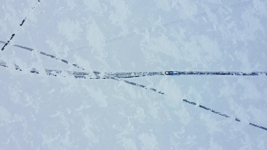 Vehicle moves along road through snow covered field