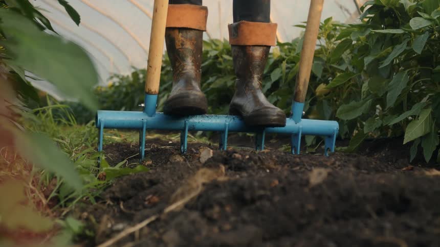 A persons feet are shown jumping on a rake that is in the dirt and trying to balance on it