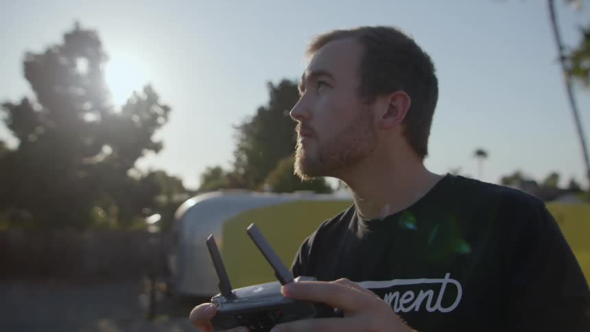 A man looks up at the sky while operating a drone