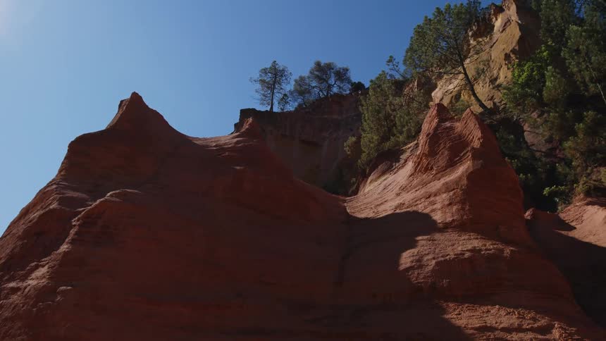Beautiful red rock canyon cliff and green trees under a bright blue sky