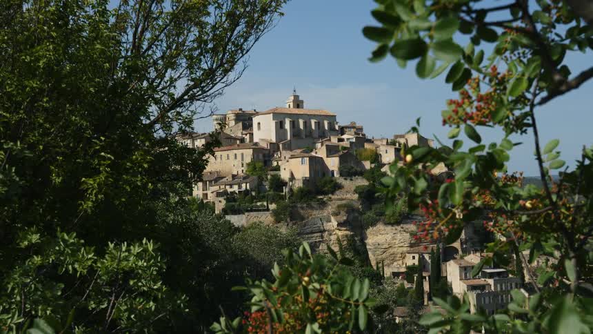 Small buildings on an european town built on the gentle slope of a hill under a blue sky