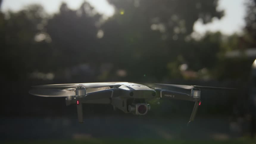 Sunlight shines on a drone as it hoovers above the ground