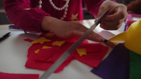 Close up of a girl using a ruler to measure where to place pieces of felt on a hand crafted decoration