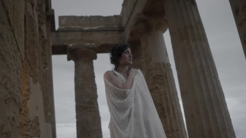 A woman is wrapped in her white robes on a windy day