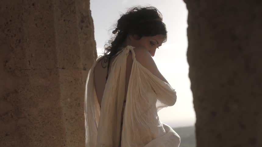 A woman is standing by a pillar on a windy day