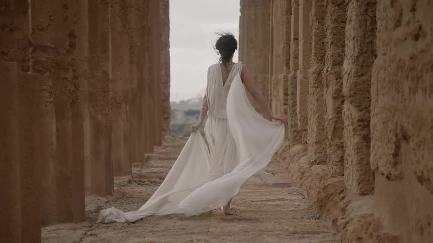 A woman walks on a cloudy day wearing white robes