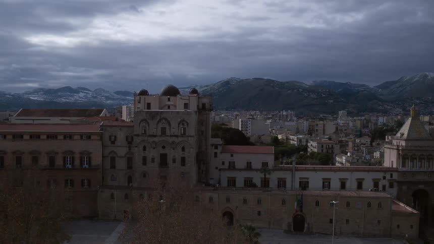 A large building sits on a hill with a city below it