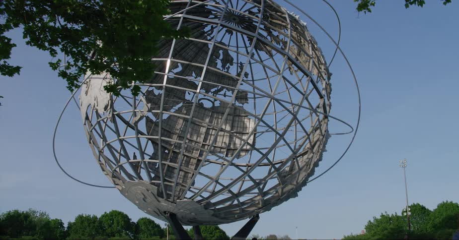 People walk past the giant globe in the park