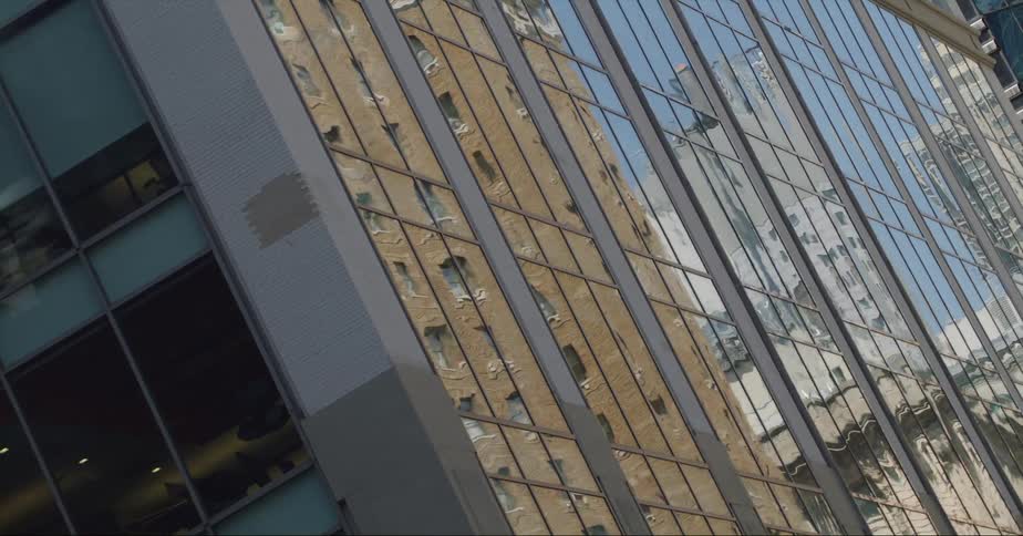 Sides of office building reflect other buildings and the sky
