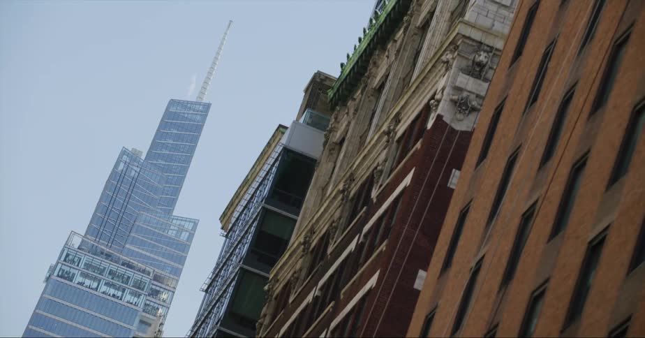 A tower with a tall spire stands near other buildings on a downtown street