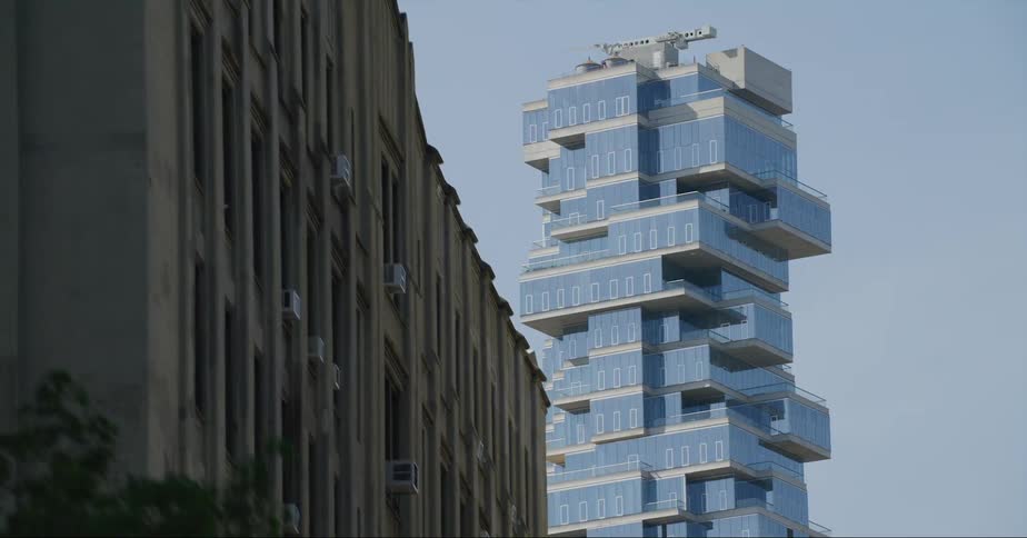 A elaborately designed skyscraper looming over smaller buildings in a metropolis during the day