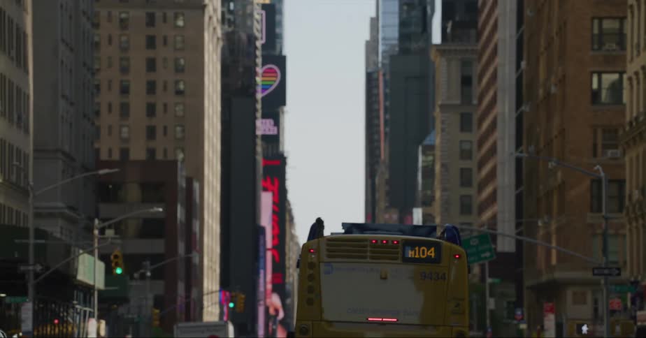 A bus moves through a busy downtown street filled with buildings and businesses