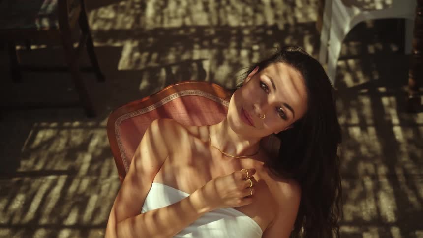 A woman with a nose piercing smiling while sitting in a chair