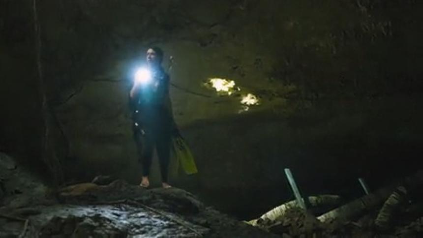A woman is exploring a cave by herself