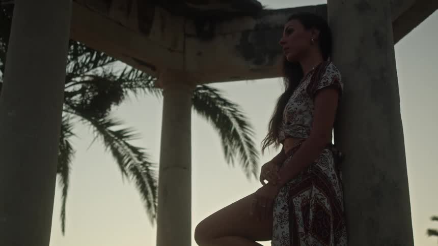 A woman is standing outdoors during sunset