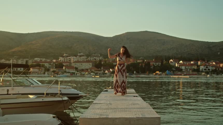 A woman is walking on a dock over the lake